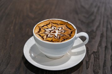 cup of beautiful hot mocha art latte coffee on table
