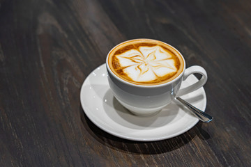 Vertical photo of latte art cappuccino coffee on wooden table