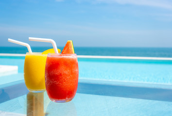 watermelon smoothie and mango smoothie with swimming pool and sea beach background