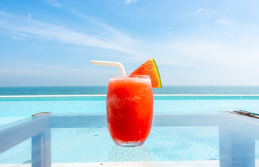 watermelon smoothie with swimming pool and sea beach background