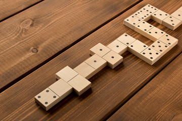 Playing dominoes on a wooden table. Leisure games concept. Selective focus.