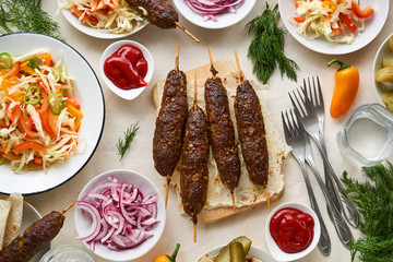 Dinner table with beef kebab, fresh salad and herbs 