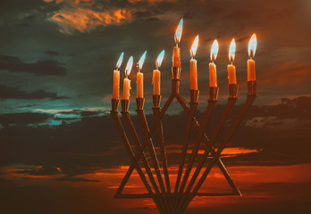 Jewish holiday Hanukkah with menorah traditional burning candles beautiful sunset