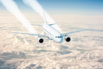 White passenger jet plane flies above the clouds. View from above