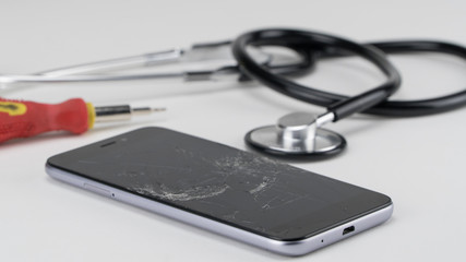 Diagnosing the phone with a stethoscope, near a screwdriver. Phone repair concept