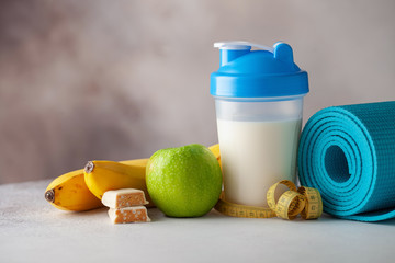 Sport equipment and food -  mat, gym shoes, block,  belt,  protein, banana, apple. Fitness concept. Copy space