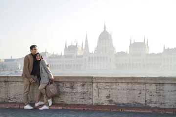 Papier Peint photo autocollant Budapest a couple posing against a river background and beautiful city buildings of budapest