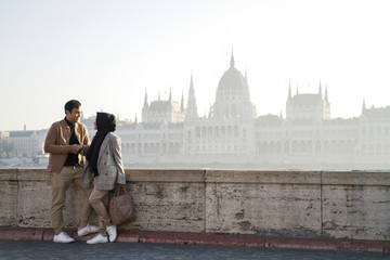 Obraz premium a couple posing against a river background and beautiful city buildings of budapest