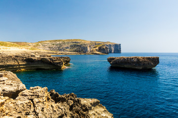 View of Dwejra Bay in Malta with its dramatic coastal formations and sea spilling over the rocks