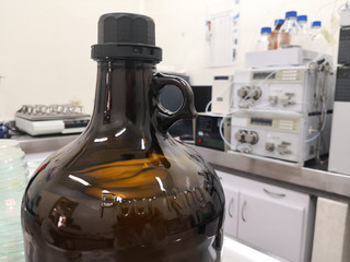 Large amber bottle for storage of chemical substances in a laboratory. Scientific equipment background.