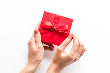 Unpack a gift on Valentine's Day. Women hand hold ribbon tied present box on white background top-down