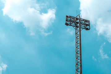 Isolated sportlights tower on blue green sky and white cloud background