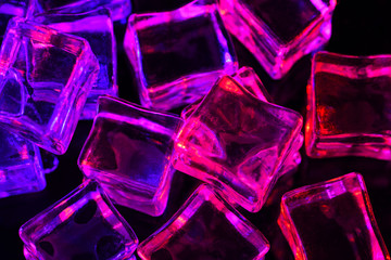 Ice cubes on black background with  pink and purple backlight. Illuminated ice cubes.  Macro...
