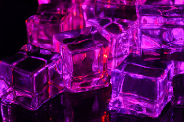 Ice cube. Close-up of melting ice cubes with pink and purple illumination on a black background....