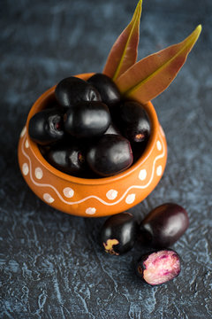 Jambolan plum or jambul or Jamun fruit, Java plum (Syzygium cumini) with leaf on stone textured background.