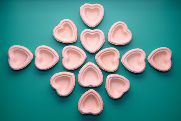 Pattern of empty tartlets in the shape of hearts. Green background. Preparation for the holiday. Molds for filling with sweets or delicacies.
