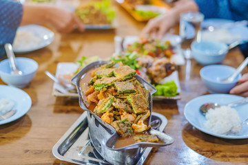 Group of female friends enjoy eating with acacia pennata omelette sour soup in fish shape hot pot in the restaurant. Selective focus.