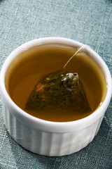 A cup of cranberry green tea with tea bag closeup
