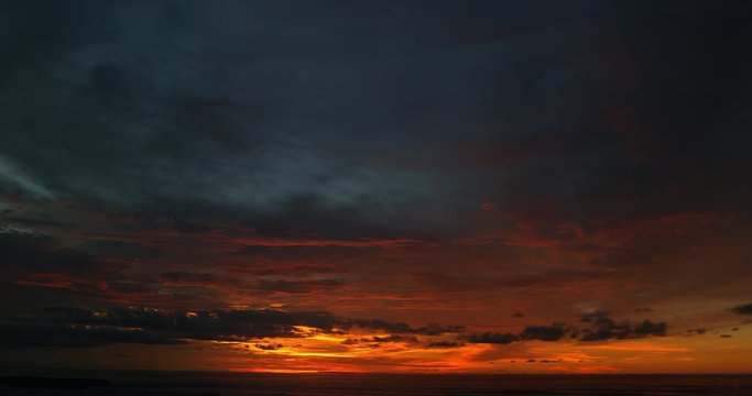 Ocean panorama. Dark orange clouds day to night sky. Dramatic sunset over storm clouds. Beautiful red color sky. Red purple orange blue pink sunset cloud background. Concept holiday in the tropics.