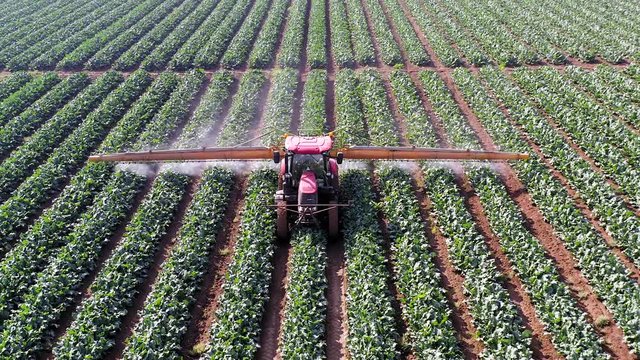 Pesticide Sprayer Tractor working on a large field, Aerial follow footage.