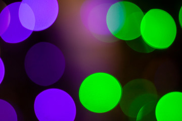 Abstract bokeh light purple and green in the night for background.