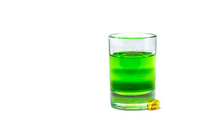 Yellow tablet and Smalll glass with a liquid, alcohol drink. Colored watery drink absinthe, curacao, cognac.