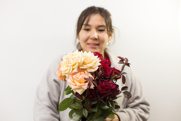 red and white roses flowers in a glass jar in the hand of a beautiful woman on a background of a white wall