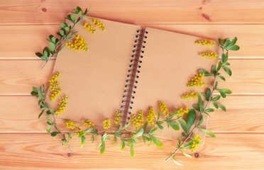 Empty notepad and yellow flowers barberry on wooden background. Top view with copy space.