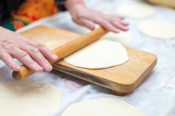 cook, female hand rolls the dough on a wooden board