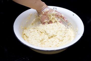 Hands of the cook prepare the dough for bread on a black background. Restrained shot with flour.