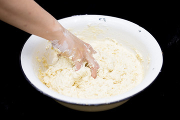 Hands of the cook prepare the dough for bread on a black background. Restrained shot with flour.
