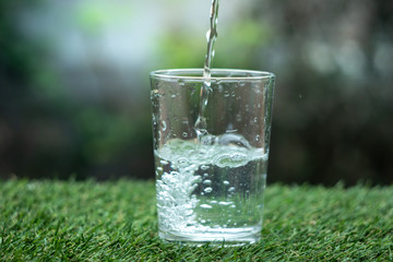 glass of water on green background of grass