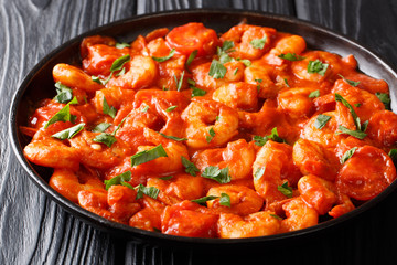 prawns with garlic and herbs in tomato sauce close-up in a plate. horizontal