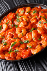 Fried shrimp in tomato sauce close-up in a plate on the table. vertical