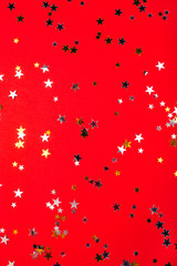 Golden and silver stars on red background. Flat lay, top view.