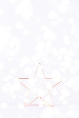 Star Copper cookie cutter on white sparkling background with bokeh lights. Holiday Christmas and New Year background. Vertical with festive bokeh lights