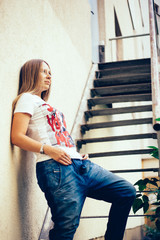 Girl European appearance in the city, urban style, jeans, t-shirt, long hair, summer