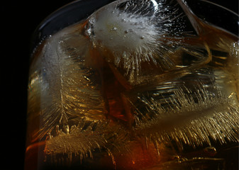textured ice cubes in a glass of whisky on dark background