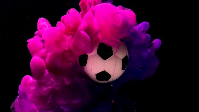 Female Football Competition Advertising Concept. Soccer ball on an amazing background. Pink and purple ink in water on a black background. A fantastic screensaver.
