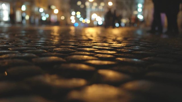 Cobblestone pavement in the city against the background of night lights. Night time, copy space