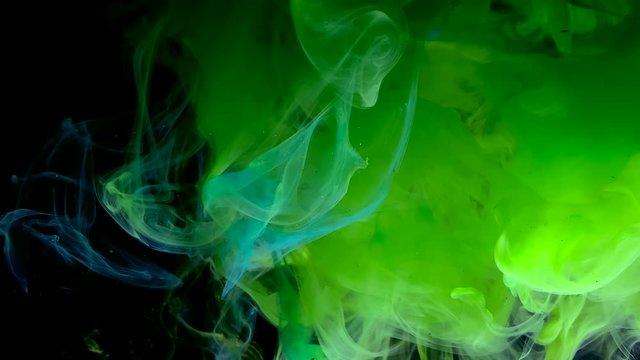 Soccer ball breaks through green smoke. Concept saver advertising football competition. Green ink in water on a black background.