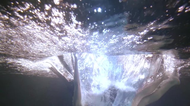 woman is falling inside water of swimming pool, underwater shot
