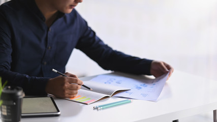 Cropped shot businessman writing conclusion his paper work and notebook.