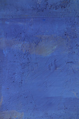 Bright blue textured background. Cement surface with cracks and scratches painted with blue paint. Close-up, top view, vertical, plenty of free space for text.