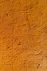 Orange textured background. Cement surface with cracks and scratches painted with orange paint. Close-up, top view, vertical, plenty of free space for text.