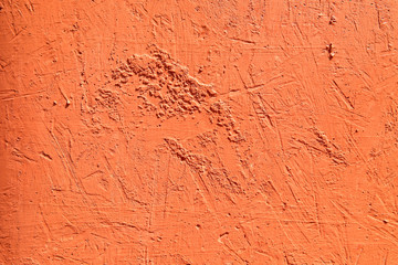 Bright orange textured background. Cement surface with cracks and scratches painted with orange...