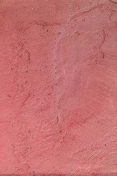 Moderate pink textured background. Cement surface with cracks and scratches painted with pink paint. Close-up, top view, vertical, plenty of free space for text.