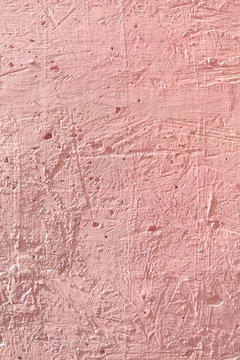 Delicate pink textured background. Cement surface with cracks and scratches painted with pink paint. Close-up, top view, vertical, plenty of free space for text.