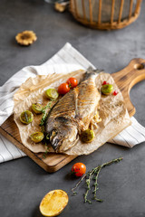 Grilled dorado with vegetables on a concrete texture background. Food photo.