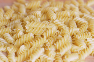 Scattered macaroni on a wooden surface close-up. Food background 